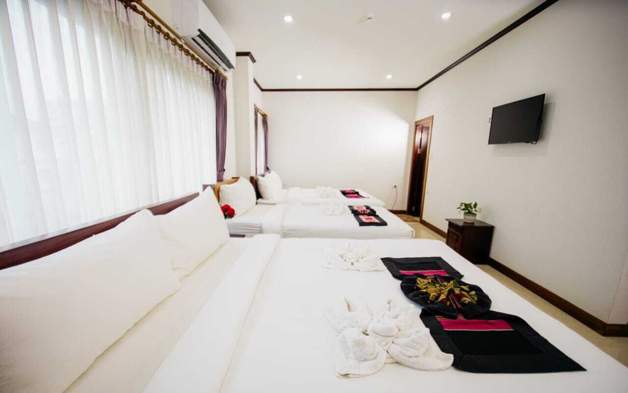 Habitación de hotel con dos camas, un televisor de pantalla plana y una pequeña mesa con una planta.
