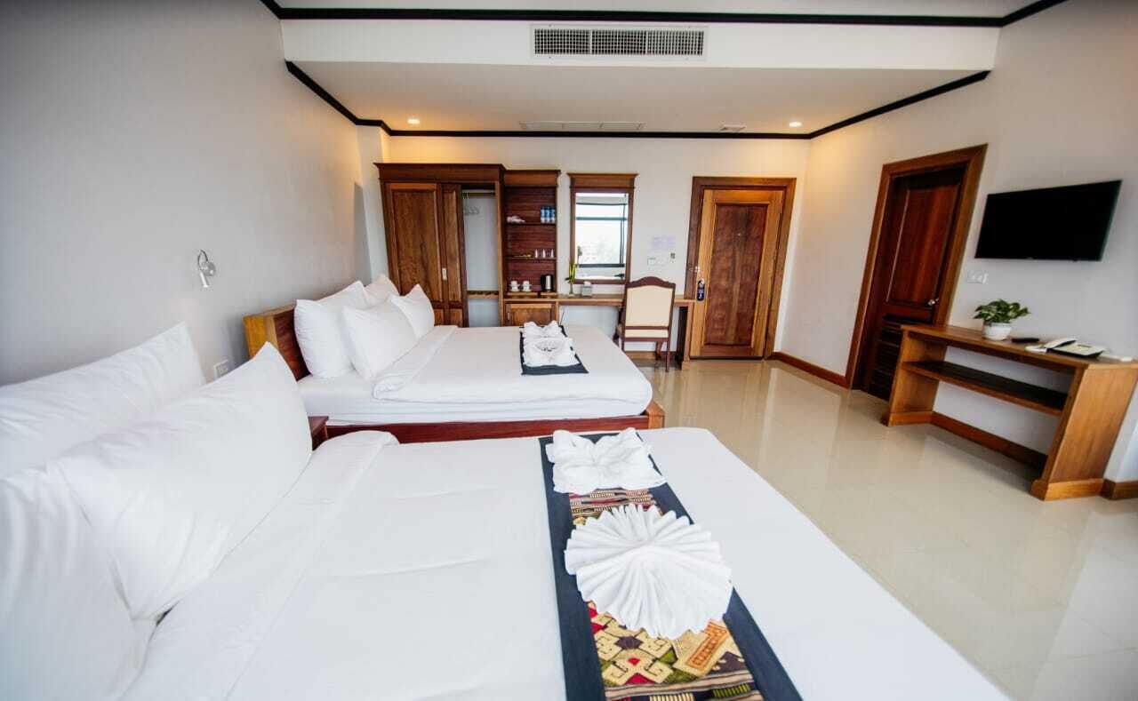 A hotel room with two beds, a TV, a desk, and a wardrobe.