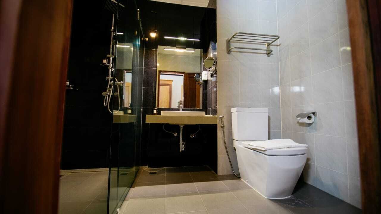 Un baño moderno con cabina de ducha de vidrio, inodoro blanco y lavamanos con espejo superior.