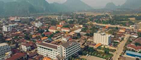 An aerial view of a town with various buildings, including a prominent hotel with multiple floors and a swimming pool.