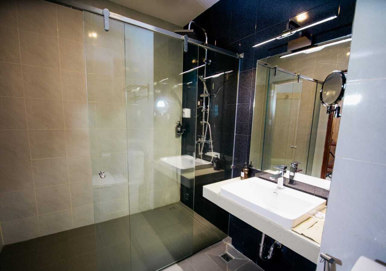 A modern bathroom with a glass-enclosed shower, a white sink, and a large mirror.