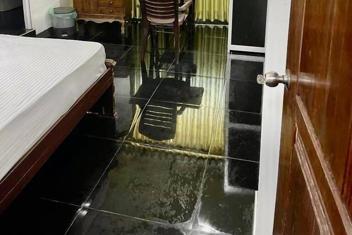 A hotel room with a bed, a desk, a chair, a mirror, and a door.