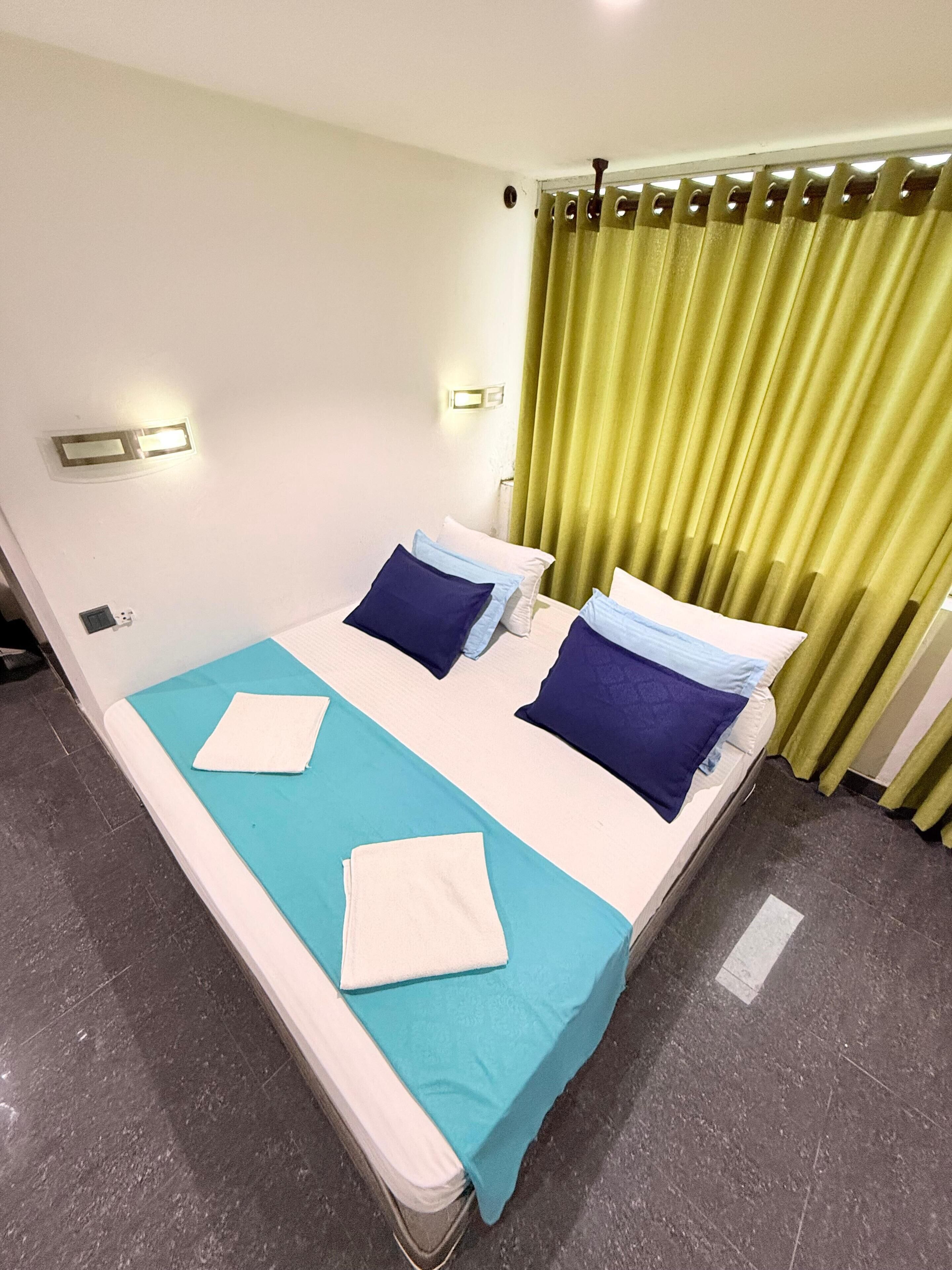 A double bed with a blue and white bedspread, two pillows, and a white towel.