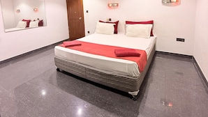 A modern bedroom with a large bed, a mirror, and wall-mounted lights. - Venus Hotel (Colombo)