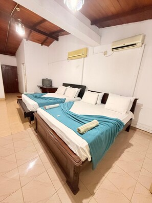 A room with two beds, a television, and an air conditioning unit. - Venus Hotel (Colombo)