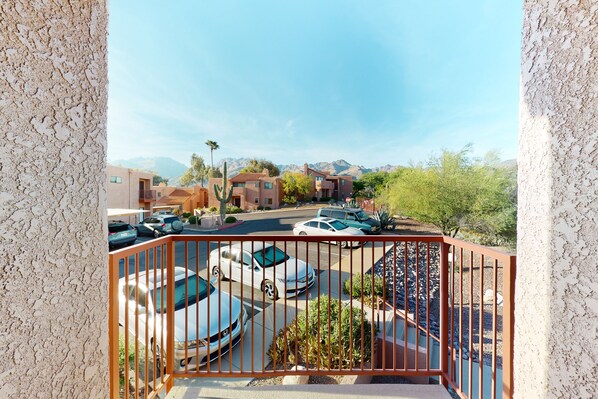 Enjoy the view from this balcony overlooking the parking area, surrounded by lush trees and shrubs.