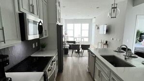 A modern kitchen with white cabinetry, a central island, and a large window providing natural light. - View with a View Waterfront WiFi,Furnished,Beaches,New Modern (Tampa)