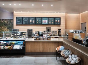 L'intérieur d'un café moderne, avec un comptoir, un espace salon et des panneaux d'affichage du menu.