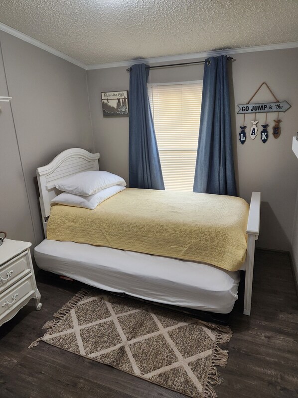 A bedroom with a bed, a dresser, a rug, and a wall decoration. - Kentucky Lake Getaway (Springville)