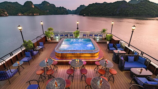 A deck with a hot tub, seating, and tables overlooking a body of water. - La Casta Cruise (Tuan Chau)