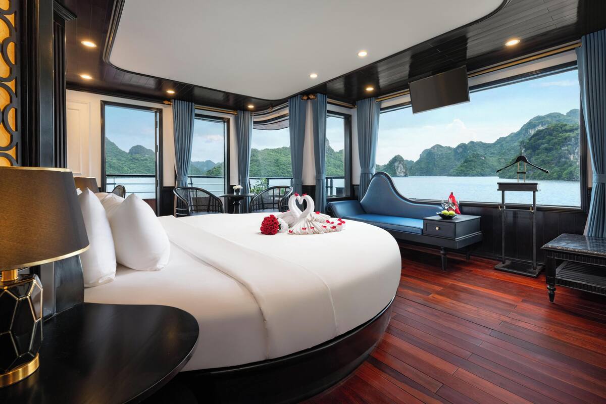 Une chambre à coucher luxueuse, dotée d’un grand lit, d’un bureau et offrant une vue sur un lac.