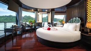 Une chambre à coucher luxueuse avec un grand lit, un coin repas et une vue sur un lac.