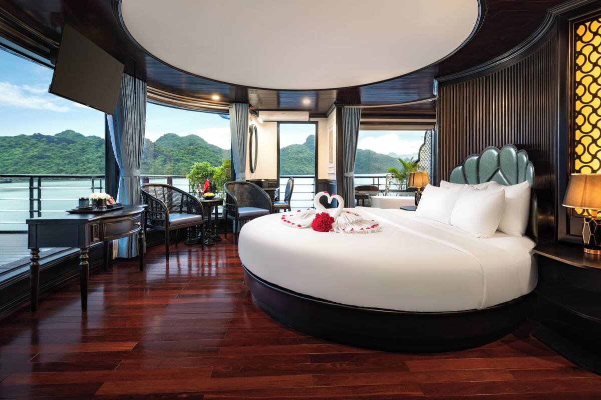 Une chambre à coucher luxueuse avec un grand lit, un coin repas et une vue sur un lac.