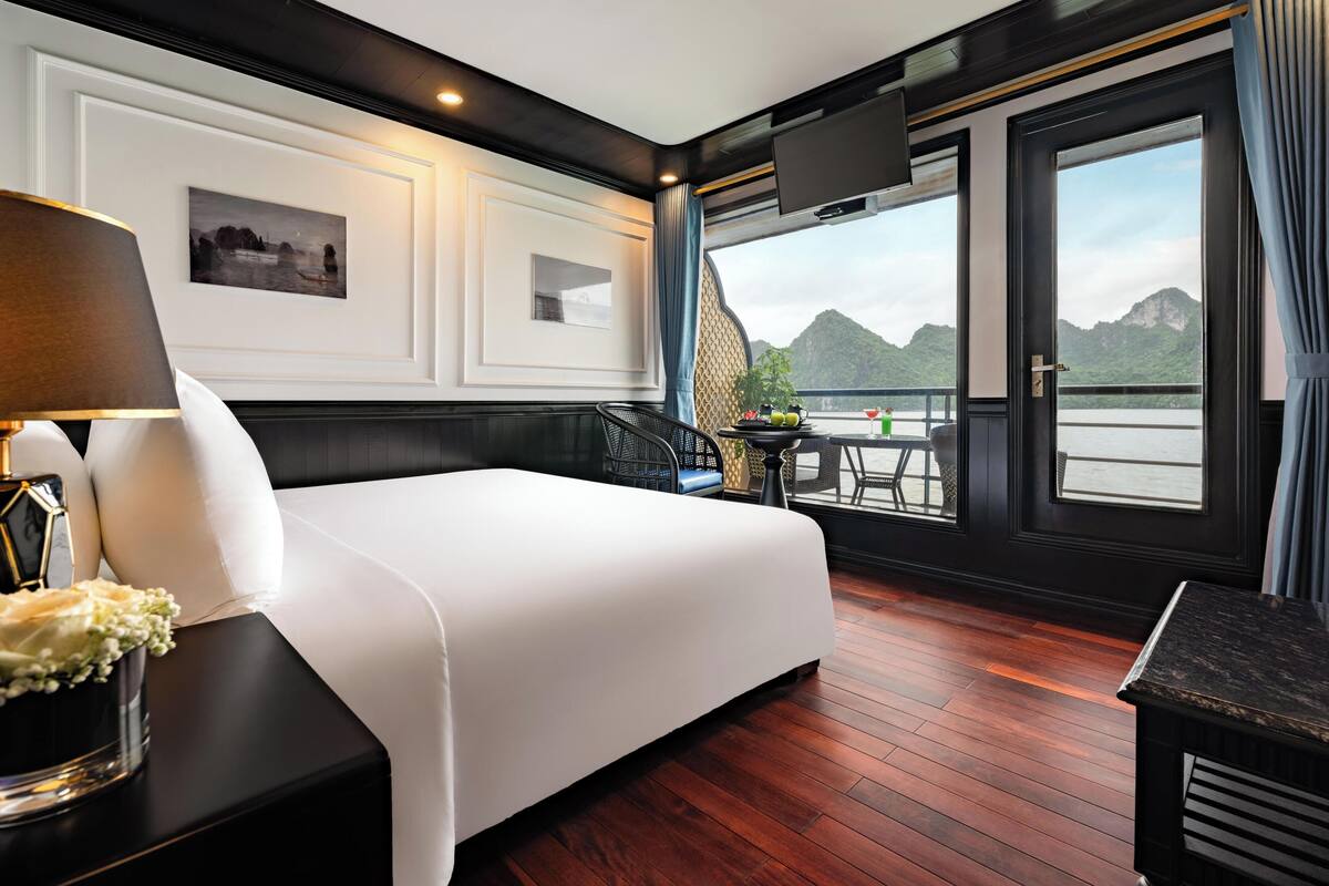 Une chambre d’hôtel avec un lit, une table avec des boissons, une chaise, un téléviseur et une grande fenêtre donnant sur les montagnes.