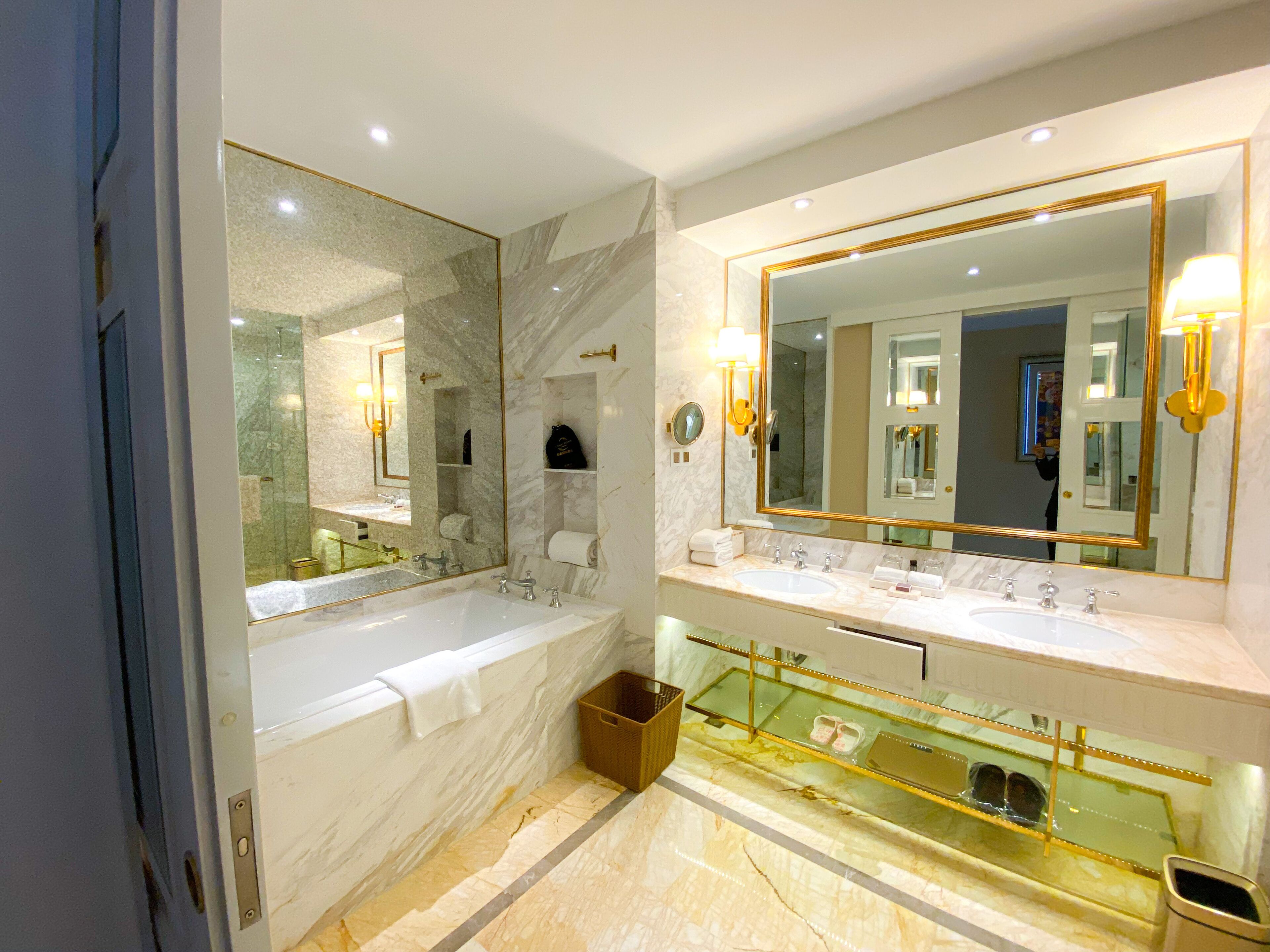 Een moderne badkamer met een groot ligbad, twee wastafels en een badkamermeubel met een glazen vitrine.