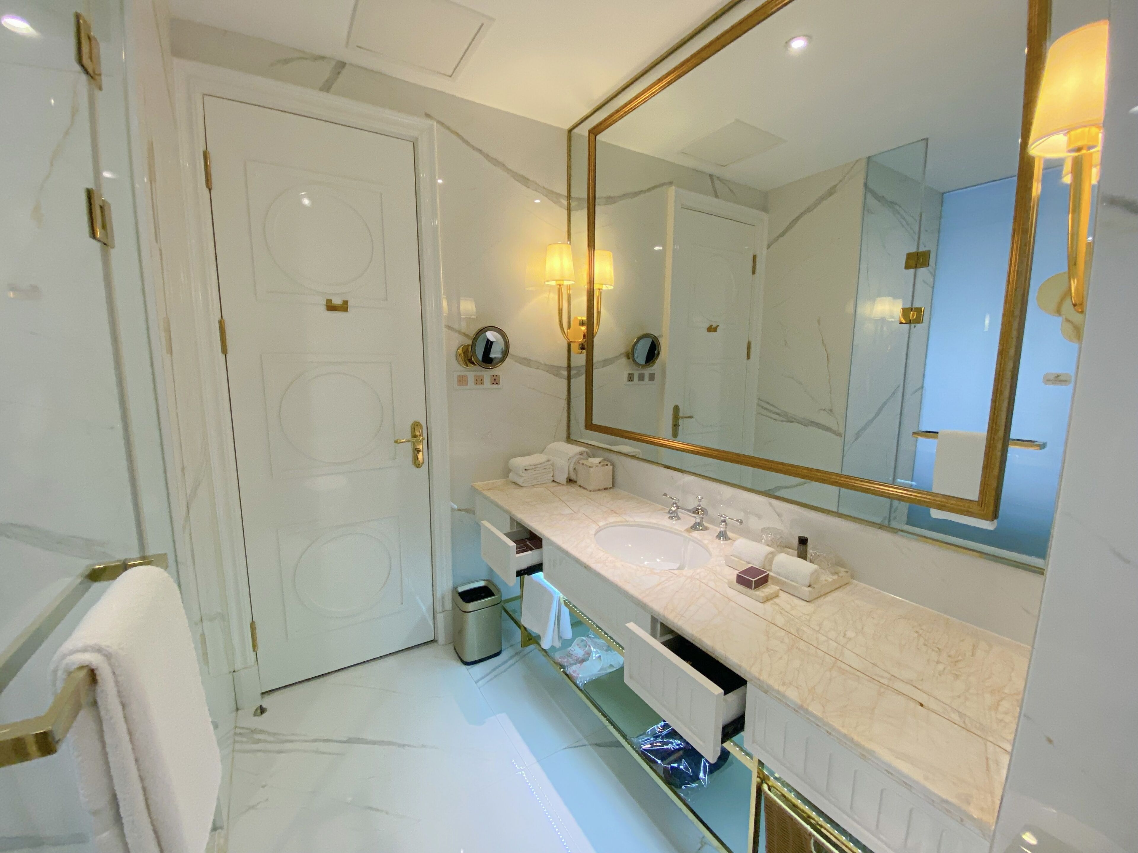 A modern bathroom with a white marble sink, a large mirror, and a gold-framed mirror.