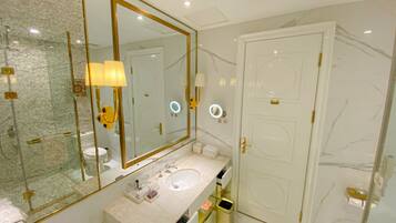 A bathroom with a large mirror, a sink, a toilet, and a door.