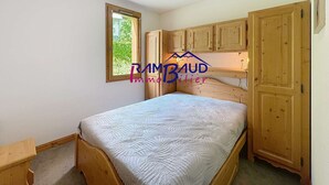 Une petite chambre avec un lit simple, des meubles en bois, une fenêtre et une porte.
