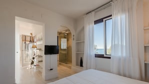 A bedroom with a large bed, a TV, a glass shower, and a view of the outdoors. - Spectacular apartment in Mont-roig (Mont-roig del Camp)