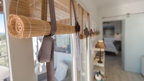 A room with a large window covered by bamboo blinds, a bed with a white headboard, and a lamp on a bedside table. - Spectacular apartment in Mont-roig (Mont-roig del Camp)