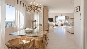 A spacious dining area with a glass table, wicker chairs, and a chandelier. - Spectacular apartment in Mont-roig (Mont-roig del Camp)