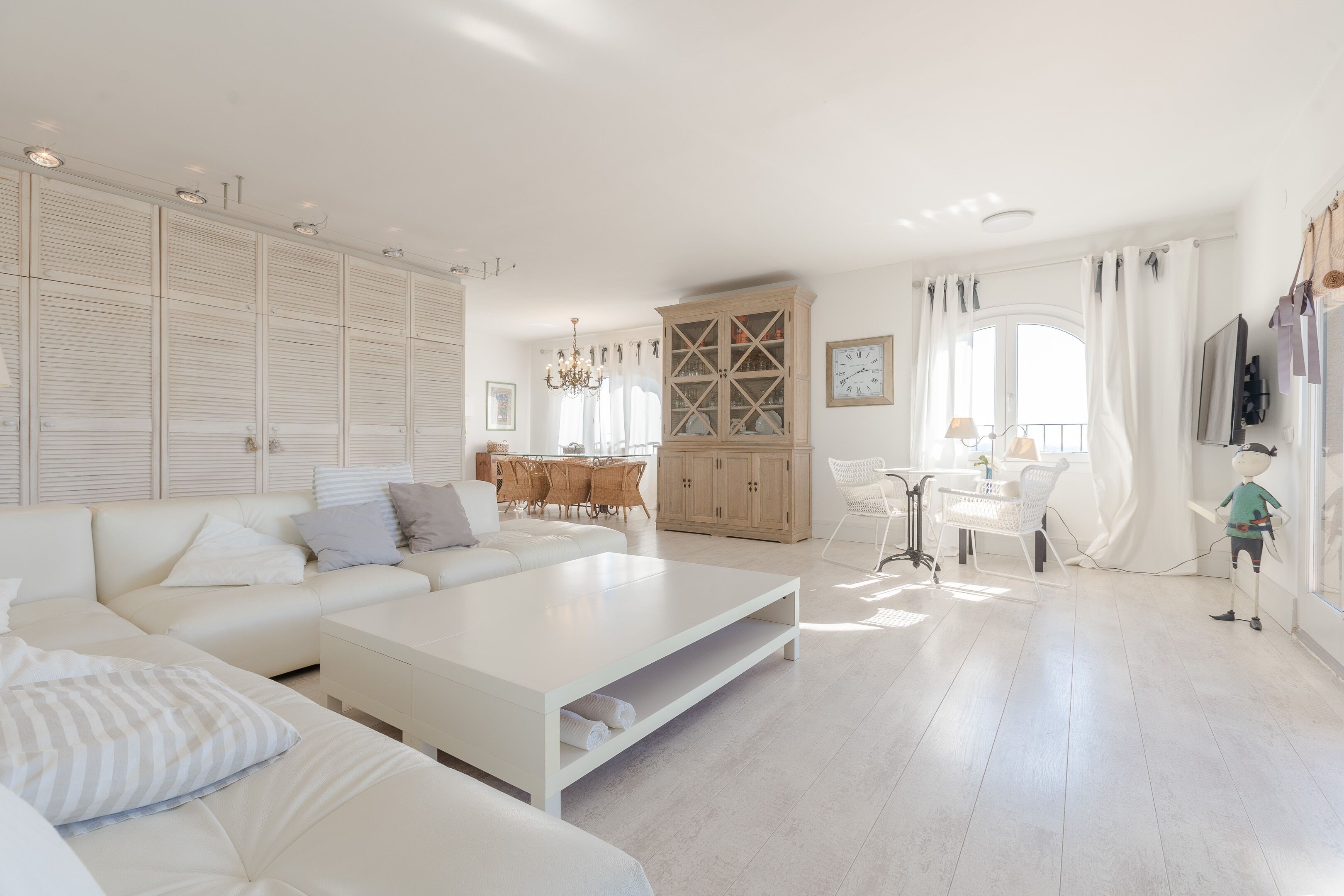 Un salón espacioso con un sofá blanco, una mesa de centro y un aparador de madera.