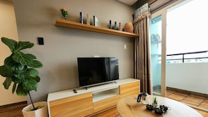 Una sala de estar moderna con televisor de pantalla plana, un mueble bajo de madera y una mesa de comedor redonda.