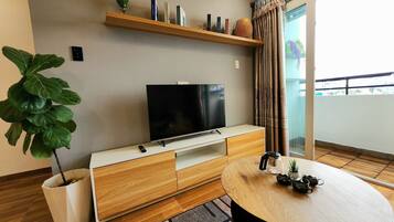 Un salon moderne avec un téléviseur à écran plat, un meuble TV en bois et une table de salle à manger ronde.