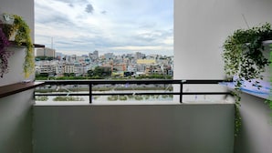 Un balcón con vista a la ciudad, plantas en macetas y barandilla.
