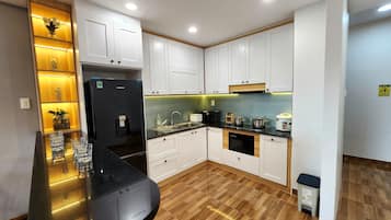 Une cuisine moderne avec des armoires blanches, un réfrigérateur noir, un évier et une cuisinière.