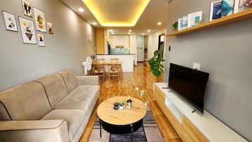 Un salon moderne avec un canapé, une table basse, un téléviseur et des étagères.