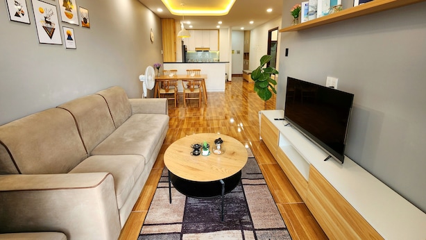 Una sala de estar moderna con un sofá, una mesa de centro, televisor y estanterías.