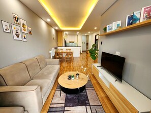 Una sala de estar moderna con un sofá, una mesa de centro, televisor y estanterías.