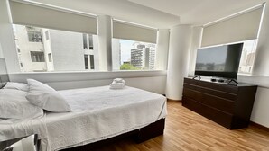 A modern bedroom with a bed, a TV, and a dresser. - Apartamento en San Isidro - A un paso del Golf! (San Isidro)