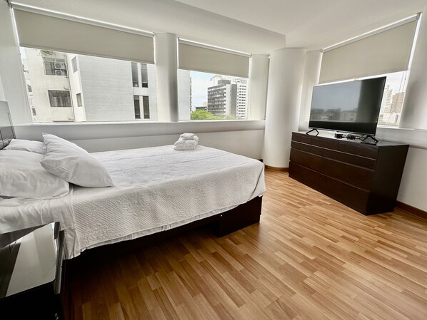 A modern bedroom with a bed, a TV, and a dresser.