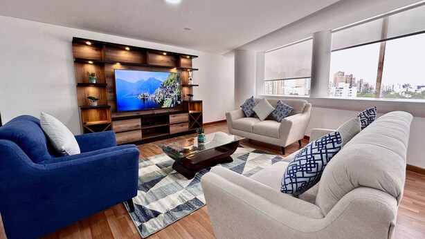 A modern living room with a flat-screen TV, wooden shelving, and a sofa set. - Apartamento en San Isidro - A un paso del Golf! (San Isidro)