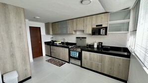 A modern kitchen with wooden cabinets, a black countertop, a microwave, and a stove. - Apartamento en San Isidro - A un paso del Golf! (San Isidro)