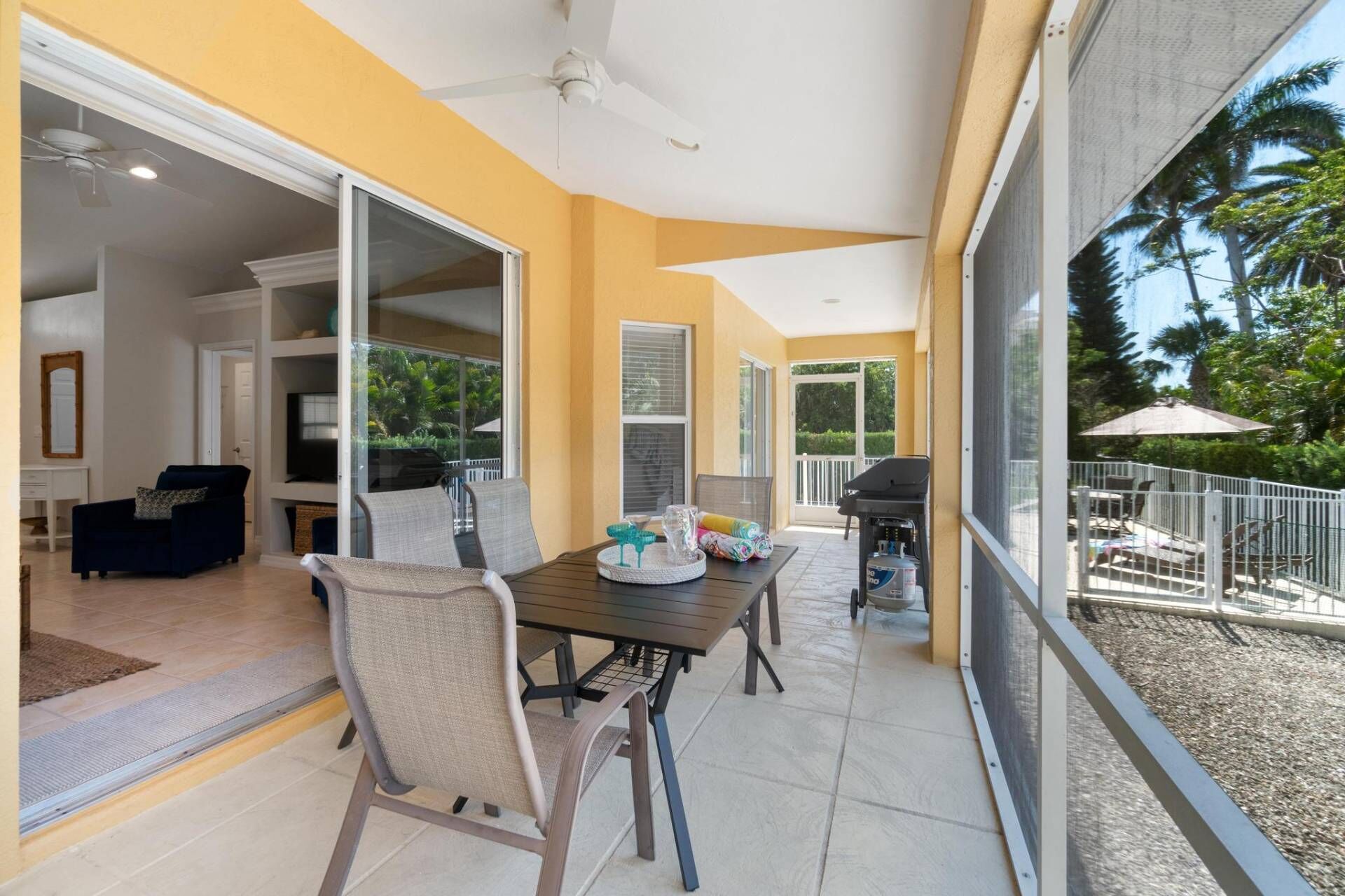 A patio area with a table and chairs, a grill, and a view of the outdoors.