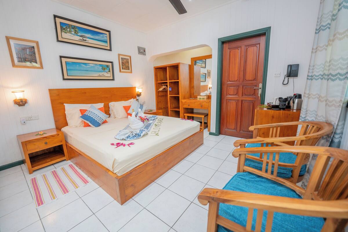 Un dormitorio ordenado con una cama de madera, mesitas de noche, un armario y una zona de estar.