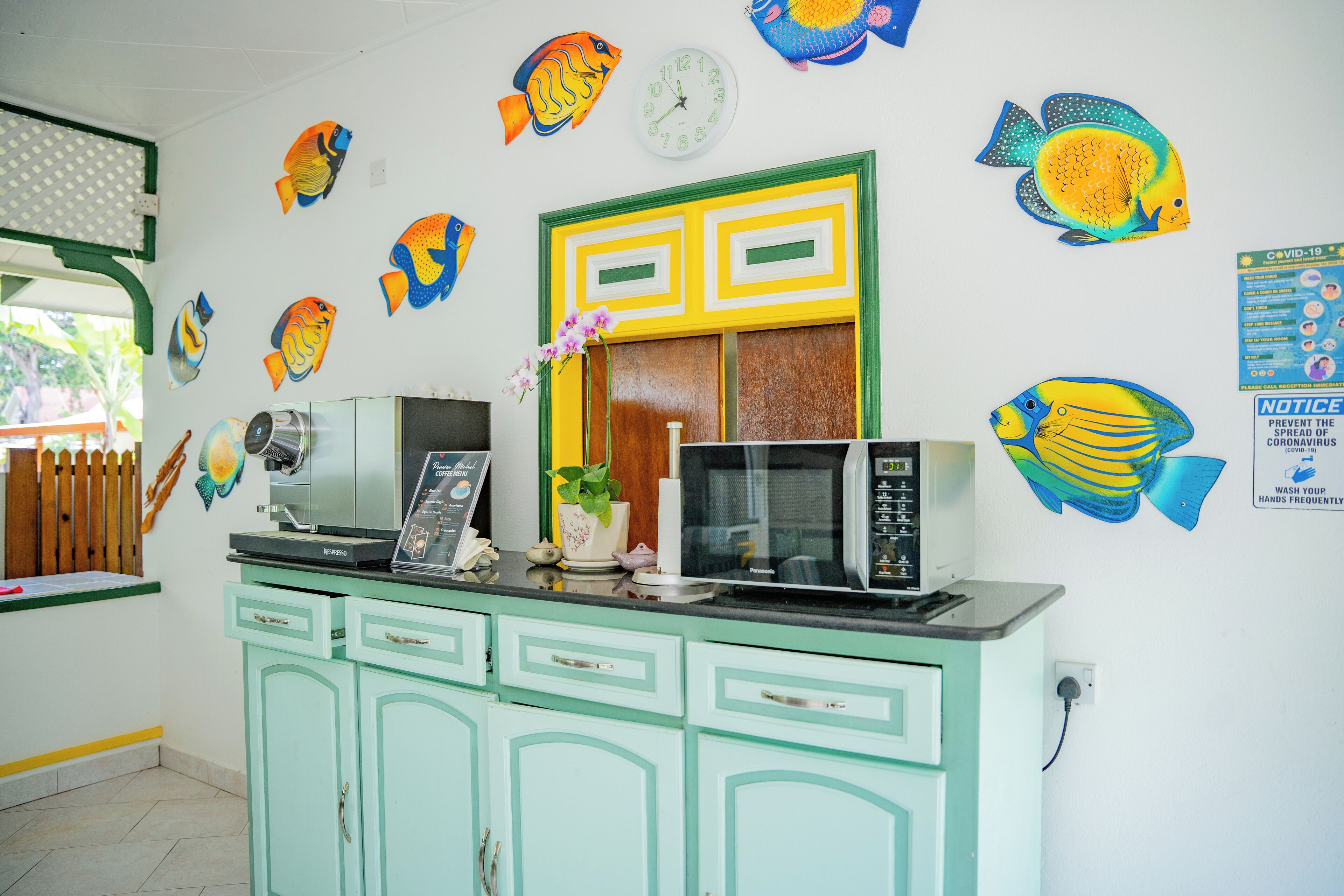 Una cocina con armarios verde azulado, un microondas y un reloj en la pared.