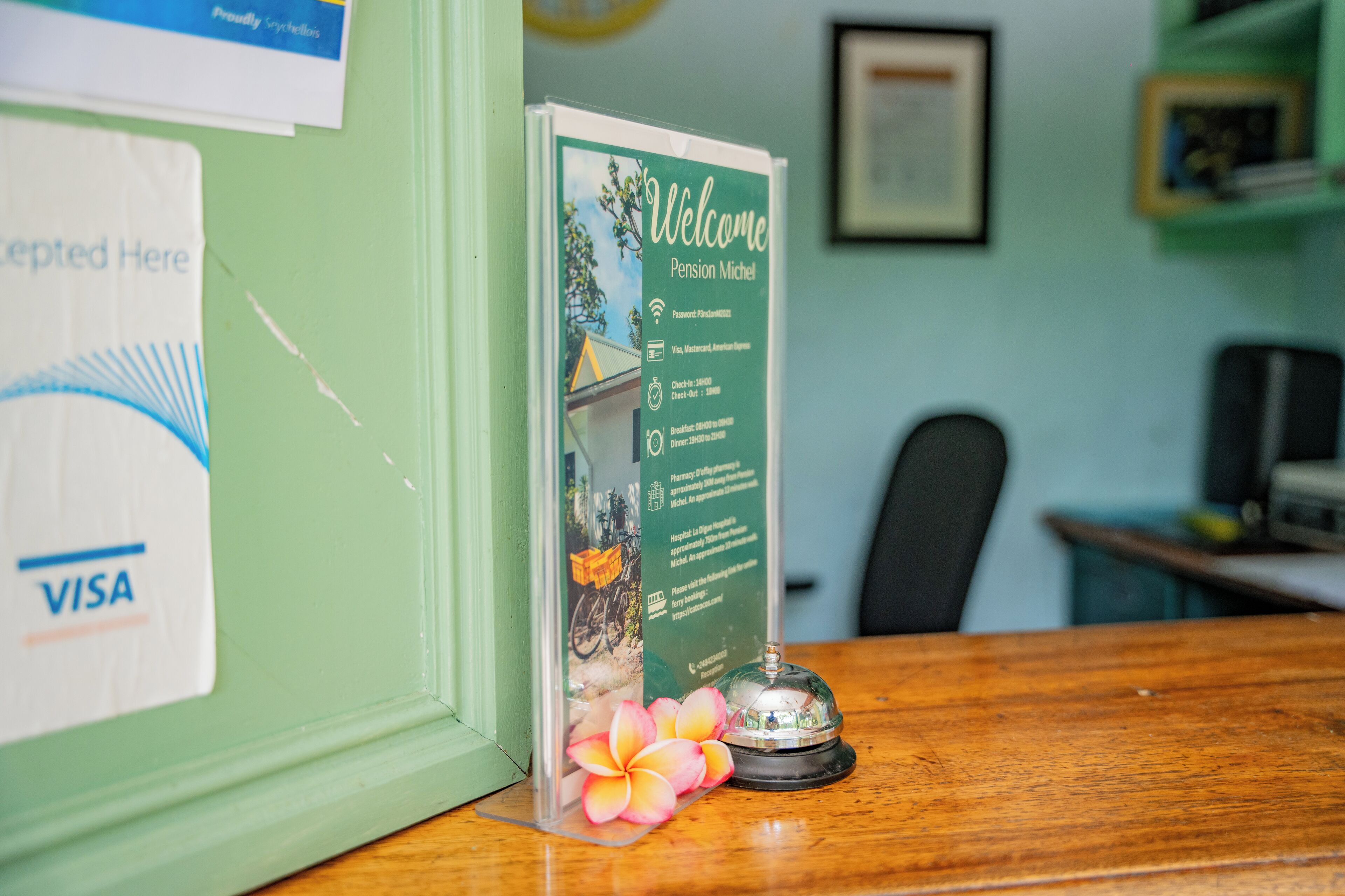 Una mesa de recepción con un cartel de bienvenida, una tarjeta Visa y una flor.