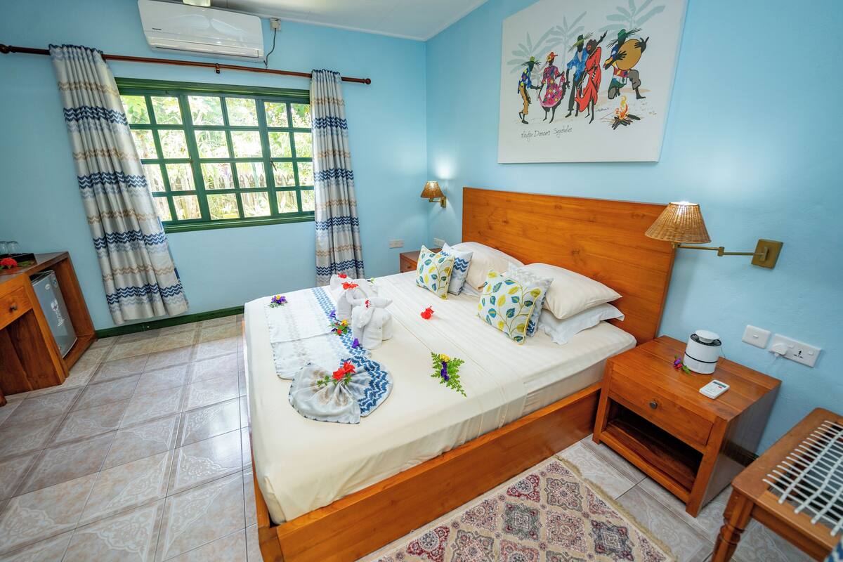 Una cama bien hecha con almohadones decorativos y una mesita de noche con una lámpara.