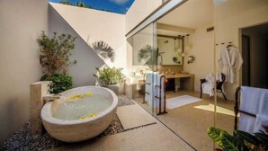 Ein modernes Badezimmer mit einer großen Badewanne, einer Duschkabine aus Glas und einem sichtbaren Waschbereich.