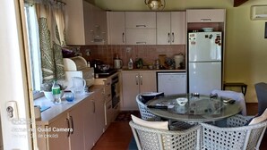 Une cuisine de taille réduite avec une table ronde en verre, des chaises en osier et un réfrigérateur.