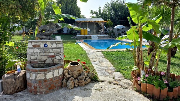 Un jardin avec un foyer en pierre, un petit étang et une piscine.