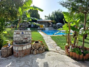 A backyard with a stone fire pit, a small pond, and a swimming pool. - Farm House in Kusadasi (Kusadasi)