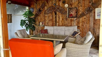Een gezellige kamer met een houten wand, een bank, een tafel en een stoel.