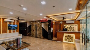 A hotel lobby with a reception desk, a staircase, a sofa, and a television. - HOTEL The Rich Grand (Agra)