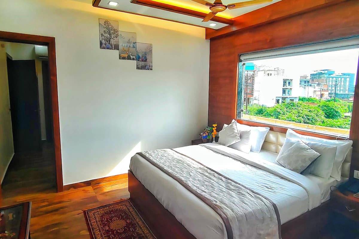 Une chambre à coucher moderne avec un grand lit, un ventilateur de plafond et une vue sur la ville par la fenêtre.