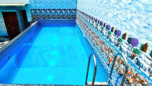 A swimming pool with a tiled border and a ladder. - HOTEL The Rich Grand (Agra)